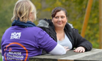 Volunteer-talking-to-a-mum-outside-on-bench-400x250